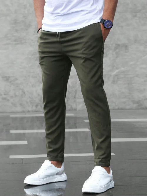 Back view of army green slim fit chino pants with drawstring waist, styled with white sneakers and a plain white t-shirt.