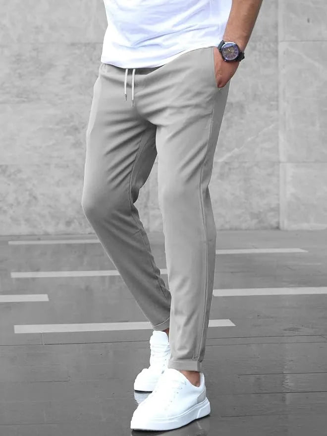 Side profile of light grey slim fit chino pants showing the tapered leg and rolled cuff hem above white sneakers.