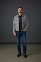 Front-facing shot of the grey trucker jacket zipped over a navy tee, styled with jeans and black boots.