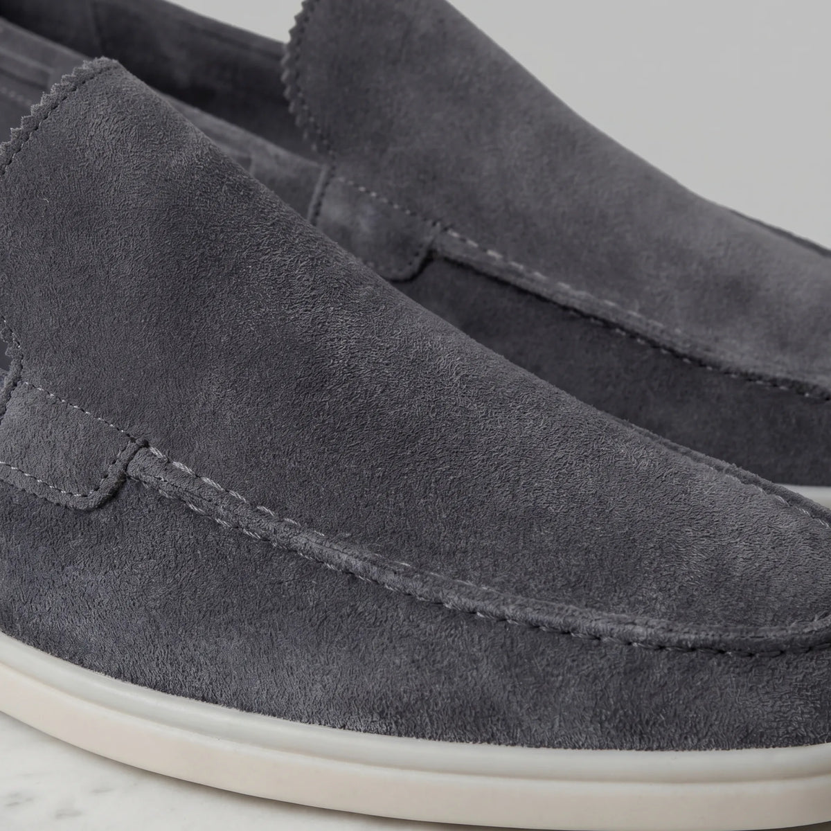 Top-down view of a taupe suede loafer showing the apron seam and suede grain