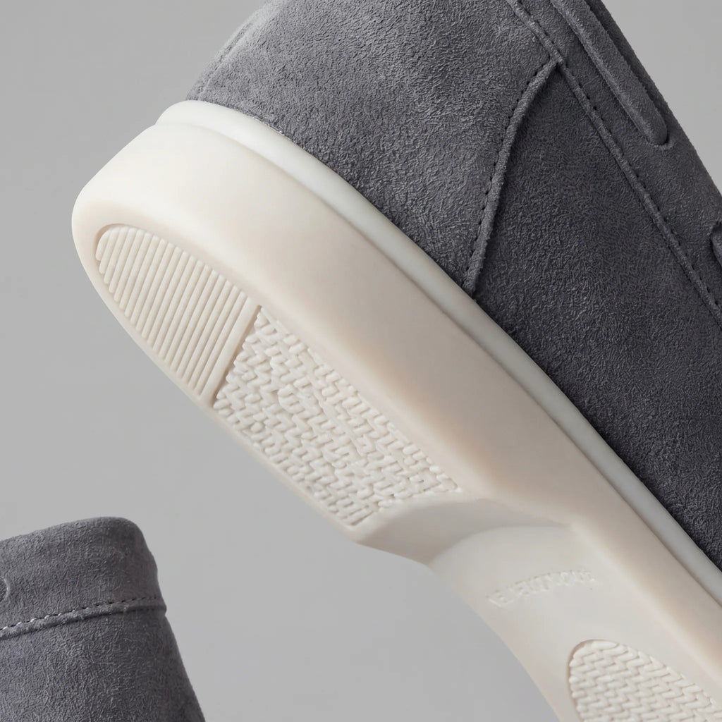 Close-up of the white rubber sole edge against the taupe suede upper