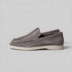 Close-up of the stitched collar and heel pull tab on a taupe suede loafer