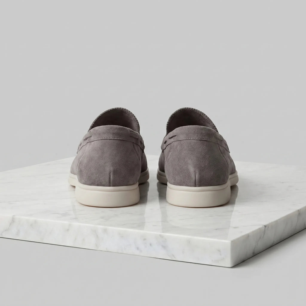 Single taupe suede loafer photographed from a low angle showing the sole thickness
