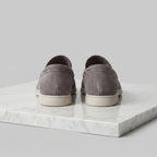 Single taupe suede loafer photographed from a low angle showing the sole thickness