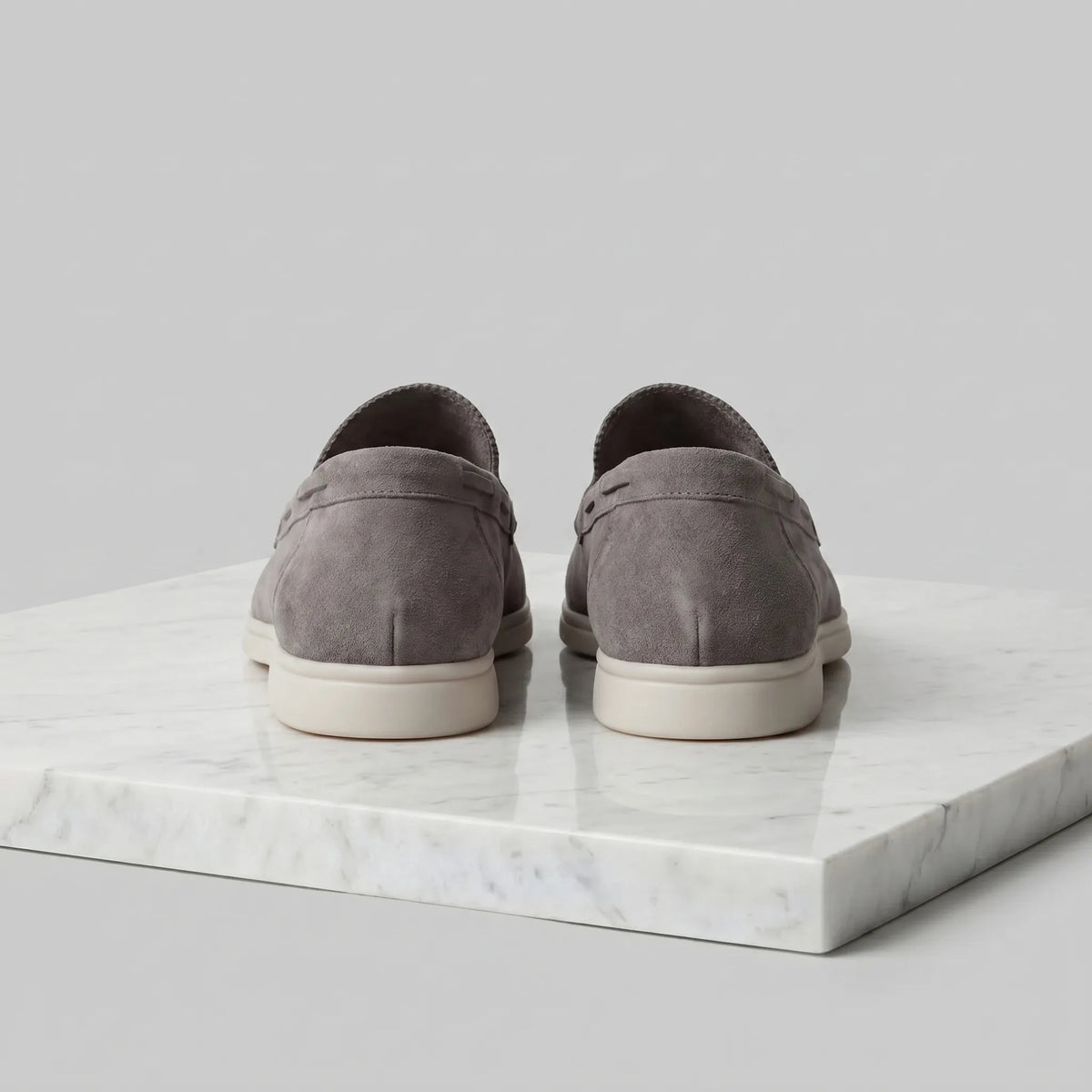 Single taupe suede loafer photographed from a low angle showing the sole thickness