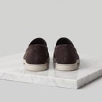 Pair of dark brown suede loafers shown in profile on a marble surface