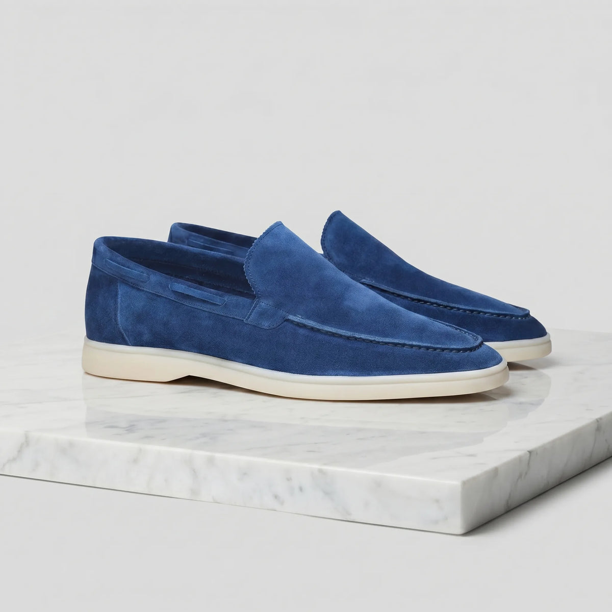 Pair of light brown suede loafers photographed side-on against a white backdrop
