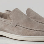 Detail shot of the apron stitching and moc-toe seam on a taupe suede loafer with white sole
