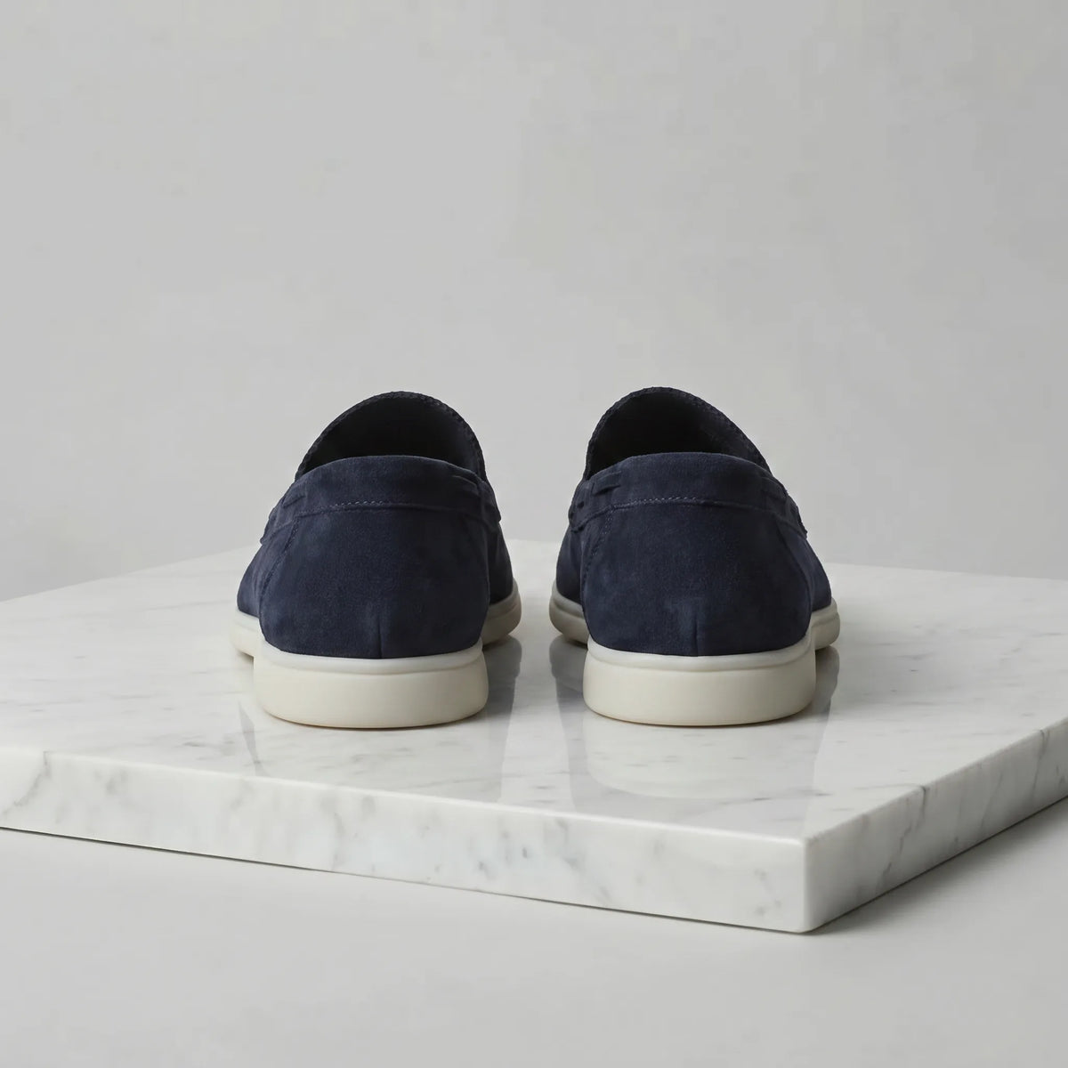 Close-up of the toe stitching and suede grain on a deep blue loafer with white sole