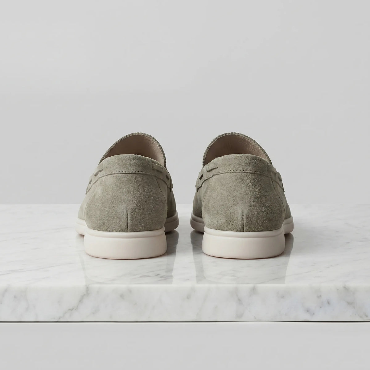 Rear view of olive green suede loafers showing the heel counter and cream outsole