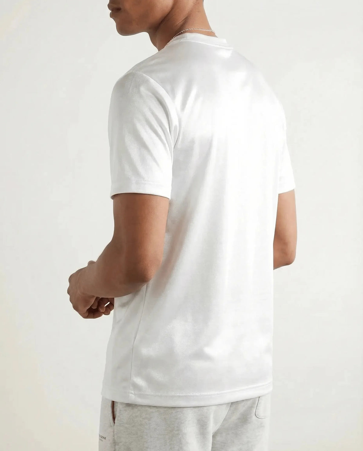 Back view showing the straight hem and clean seam construction of the white cotton tee