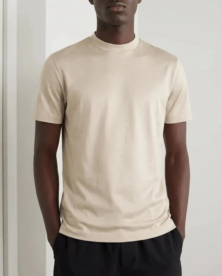 Front view of model wearing a beige mercerised cotton t-shirt paired with black trousers