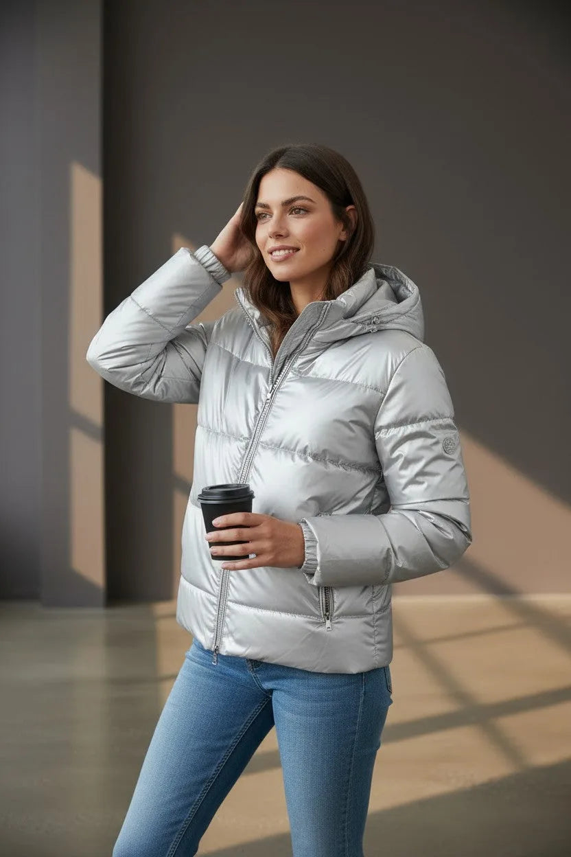 Woman in silver puffer jacket holding a coffee cup, showing the arm pocket and quilted panels