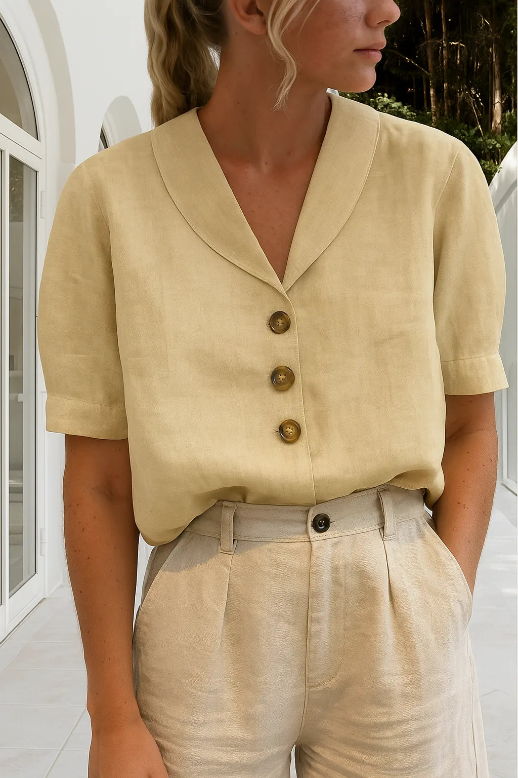 Pale beige blouse with notch collar, three brown buttons and short cuffed sleeves against a sunlit courtyard
