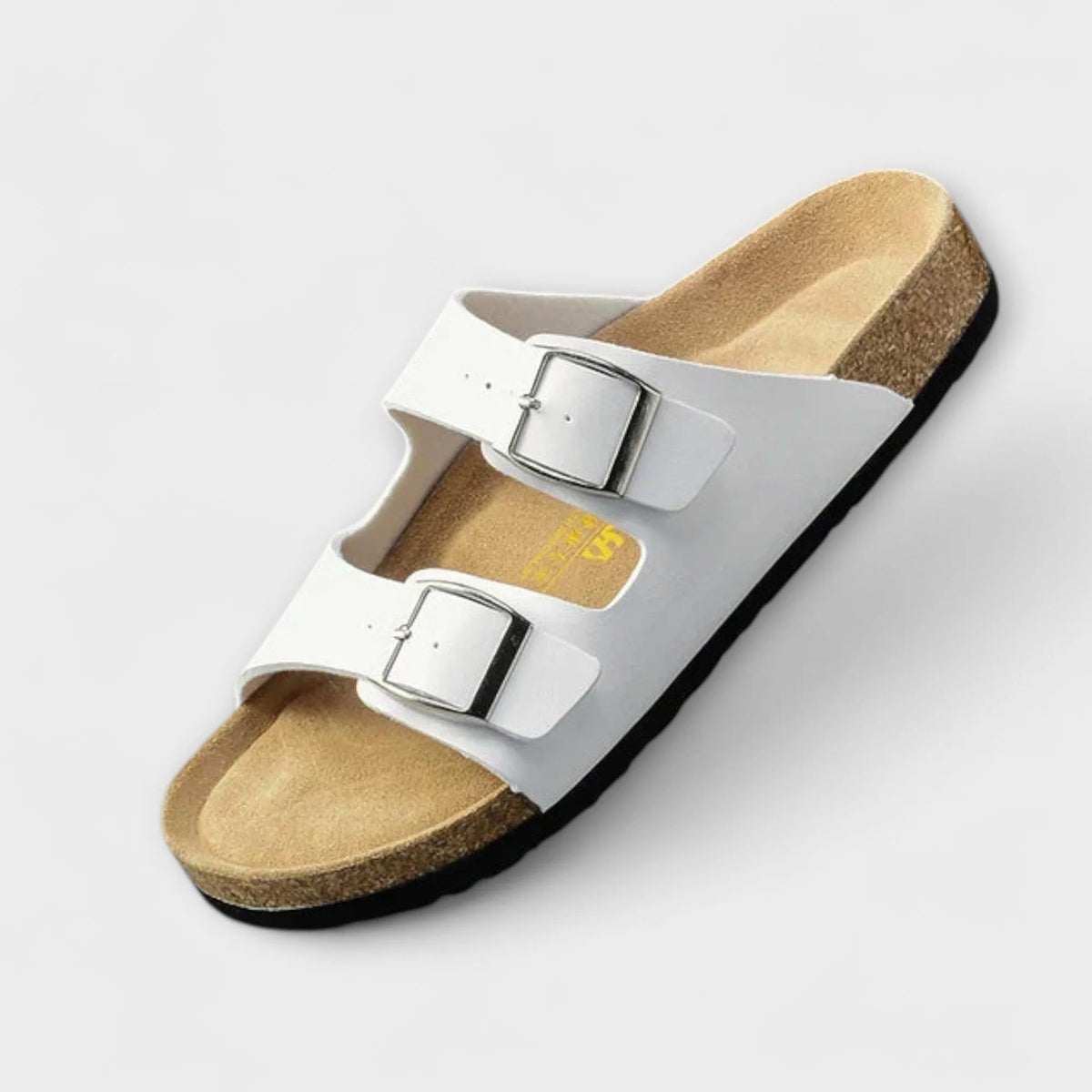 White two-strap buckle sandal angled to show the smooth upper, metal buckles and contoured cork sole