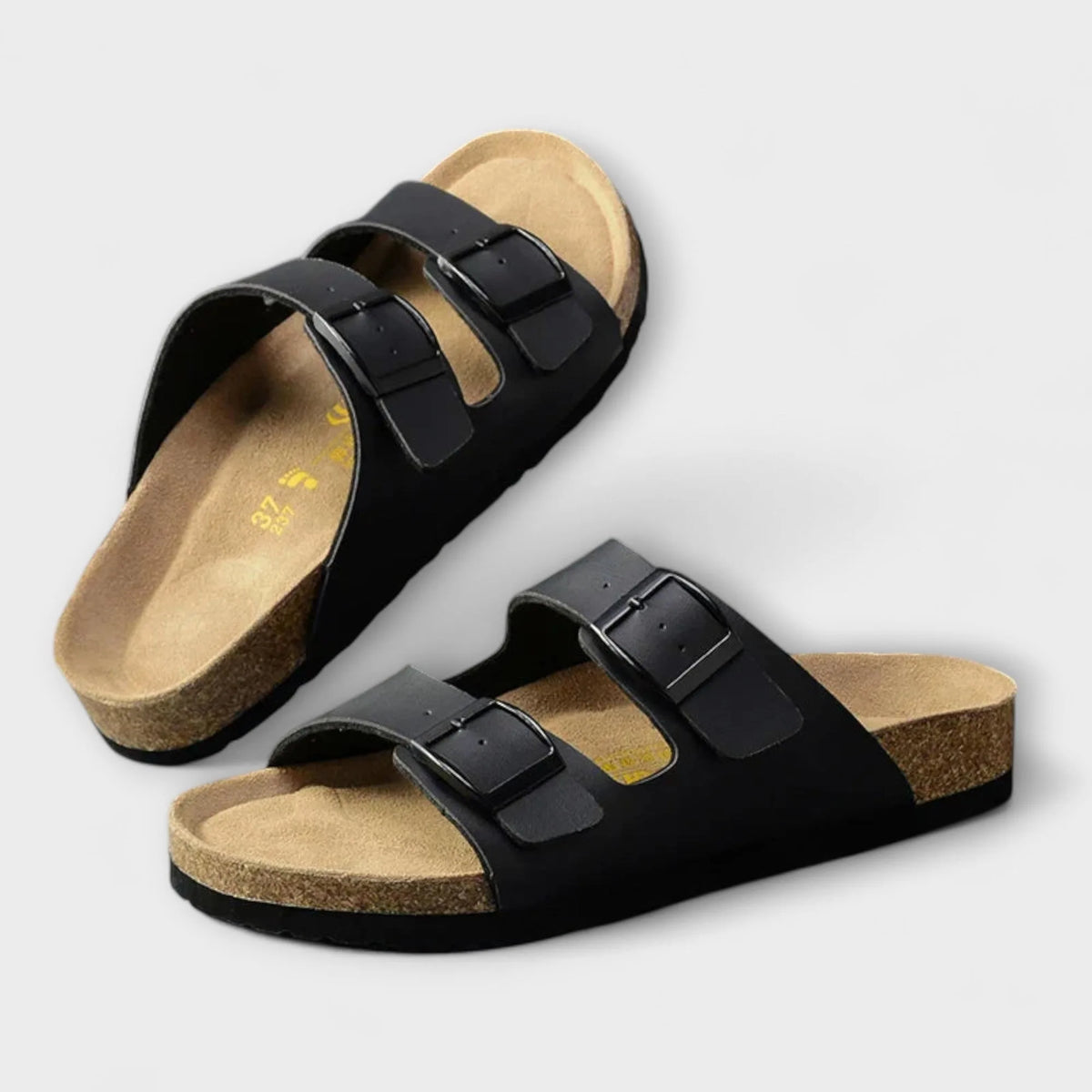 Pair of black two-strap sandals viewed from above, showing the buckle fastenings and cork platform sole
