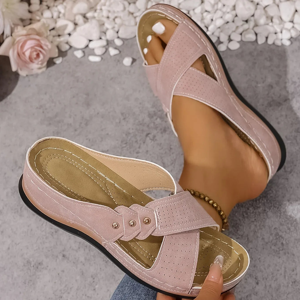 Close-up top view of blush pink criss-cross wedge sandals with gold stud detailing on the straps