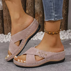 Side profile of blush pink wedge sandal with perforated straps and contrast stitching on a model's foot