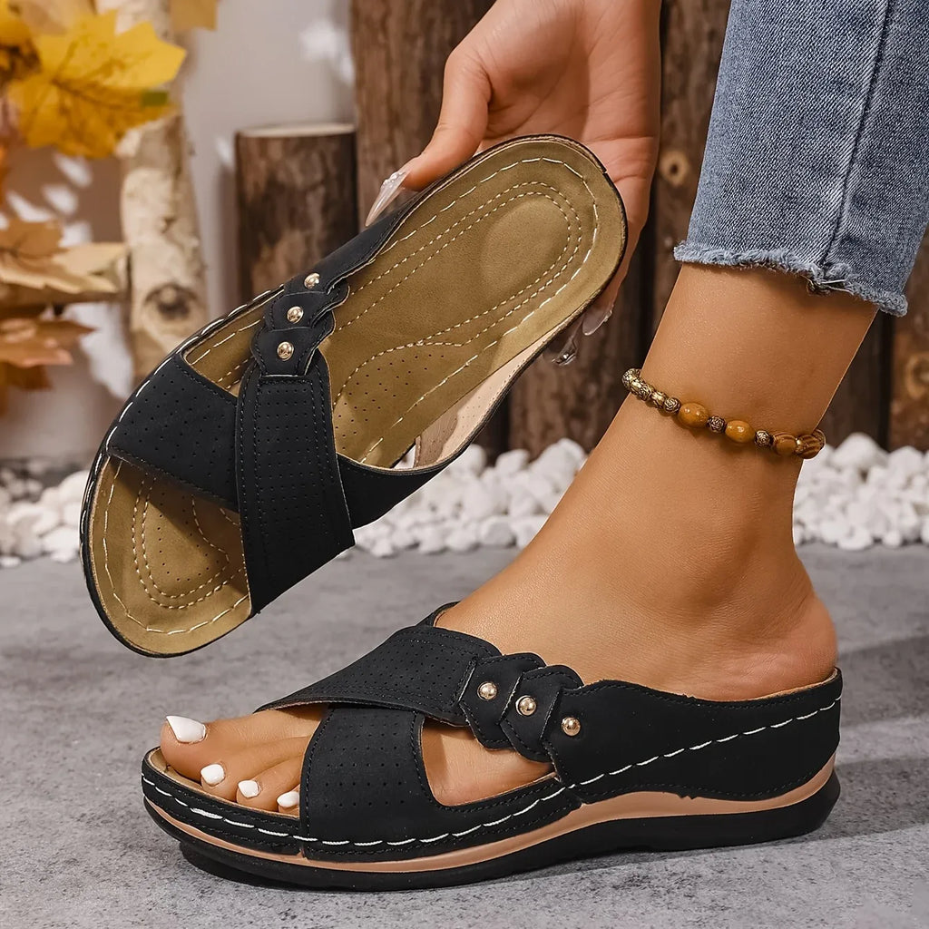 Overhead view of blush pink wedge sandals paired with denim, showing open-toe crossover design