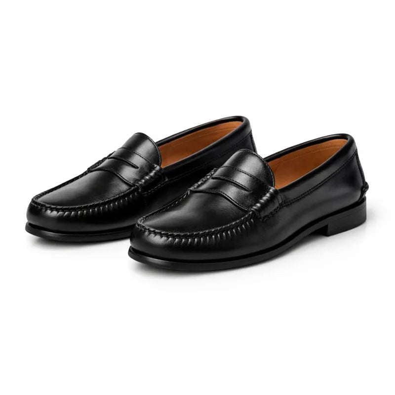 Studio pair shot of black leather penny loafers on a white background, showing tan leather lining and stacked heel.