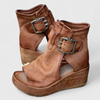 Side-by-side view of tan leather wedge booties with double buckle straps and open toe, wooden platform wedge sole