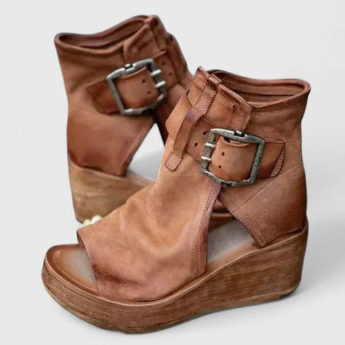 Side-by-side view of tan leather wedge booties with double buckle straps and open toe, wooden platform wedge sole