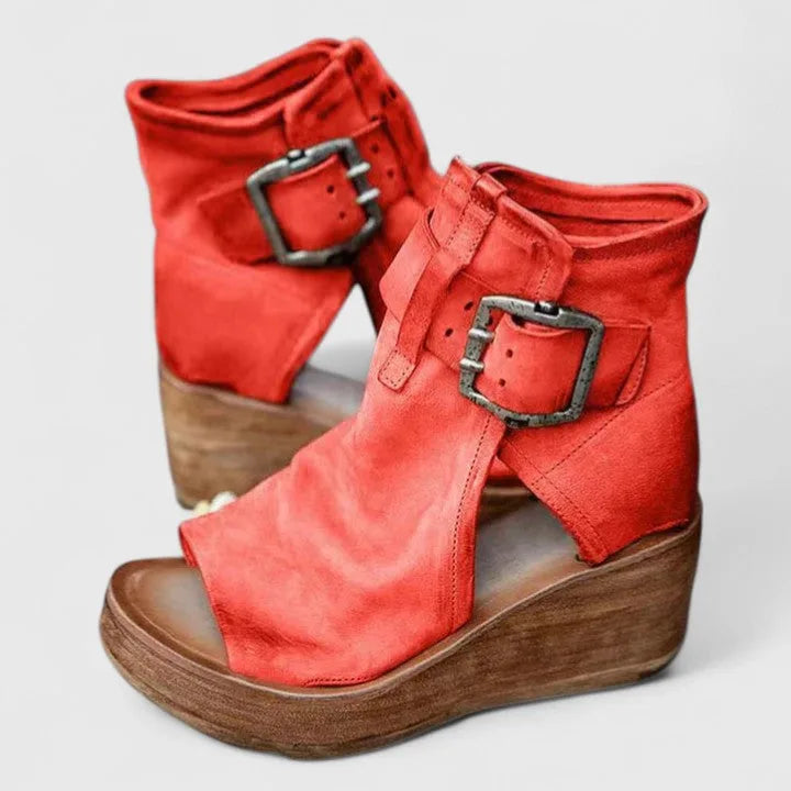 Pair of red leather wedge booties with double buckle straps, peep toe and wooden wedge platform