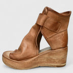 Side profile of tan leather wedge bootie with wide velcro ankle strap, open toe and wooden wedge sole