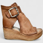 Side profile of tan leather wedge bootie with large silver buckle, cut-out ankle and wooden platform heel