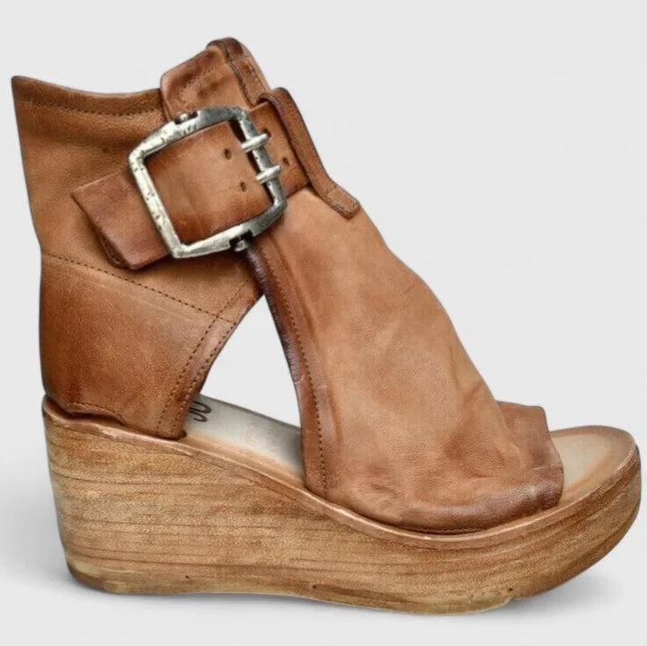 Side profile of tan leather wedge bootie with large silver buckle, cut-out ankle and wooden platform heel