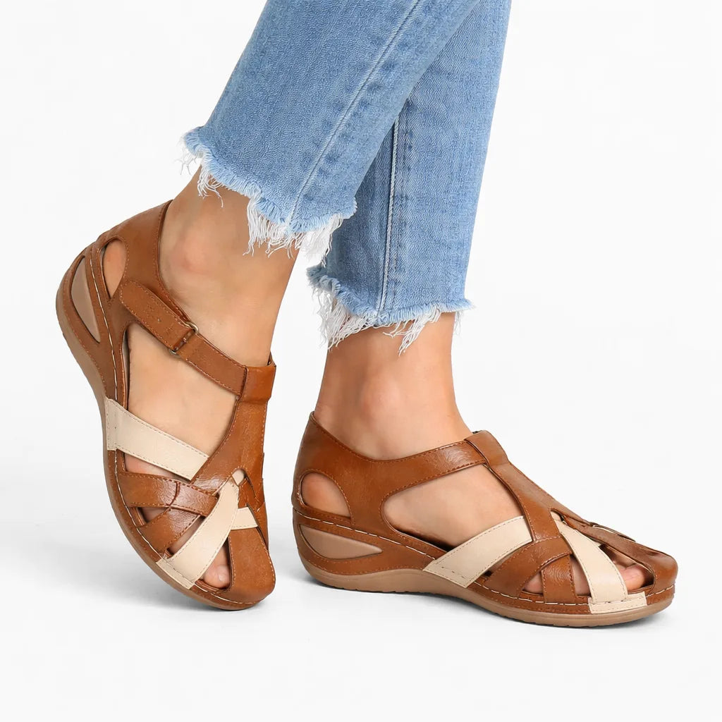 Side view of tan brown leather fisherman-style sandal with cream crisscross straps and buckle ankle strap, worn with cropped jeans