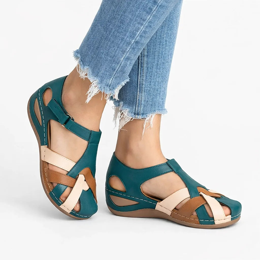 Teal leather wedge sandal with cream and brown crisscross straps across the foot and perforated side cutouts