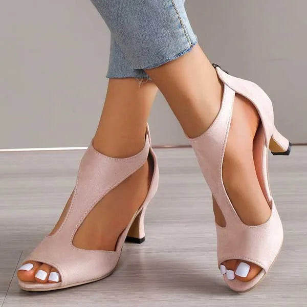 Side view of blush pink suede heeled sandal with T-strap cutout design and peep toe, worn with cropped jeans