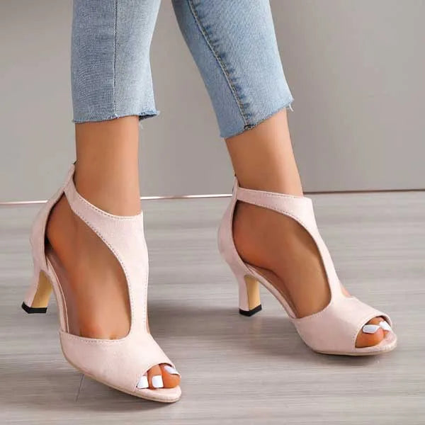 Close-up side profile of pink T-strap heeled sandal showing curved cutout panel and low block heel