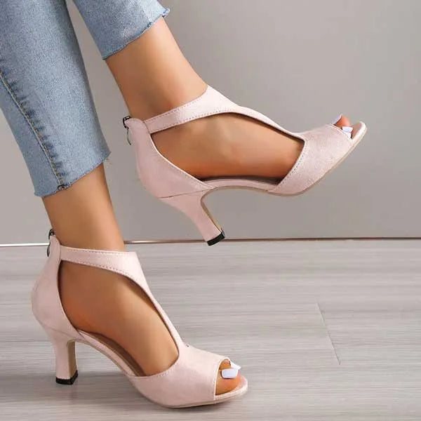 Pair of pink T-strap heeled sandals shown mid-stride, highlighting the curved side cutouts