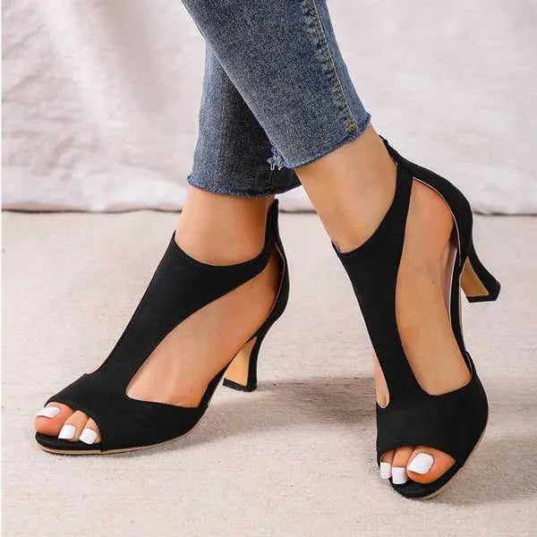 Pink suede T-strap sandal captured from the side with foot lifted, showing sole and heel height
