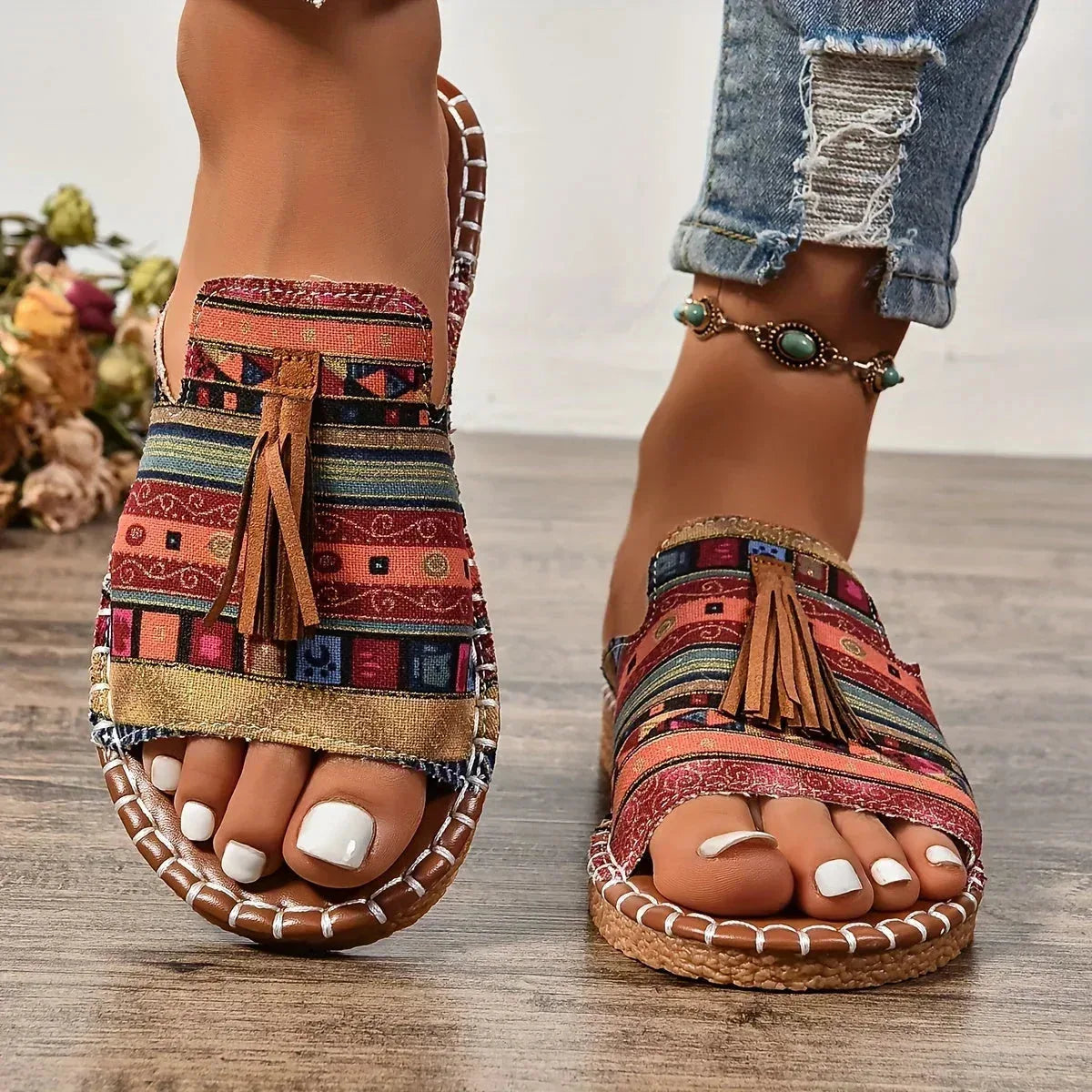 Front view of boho tribal-print sandals with tan whipstitch sole, tan anklet strap and suede tassel detail