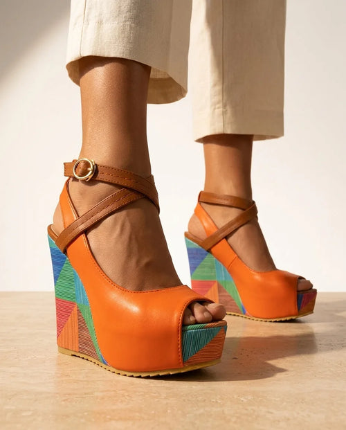 Close-up side view of orange leather platform wedge sandal with tan crisscross ankle straps and multicolour geometric wedge heel