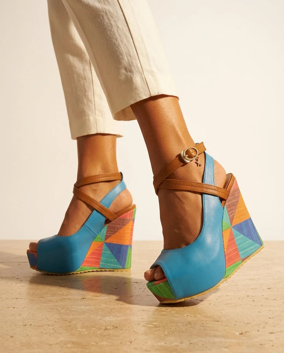Rear view of light blue platform wedge sandal showing tan crossover ankle strap, gold buckle and colourful patterned wedge sole