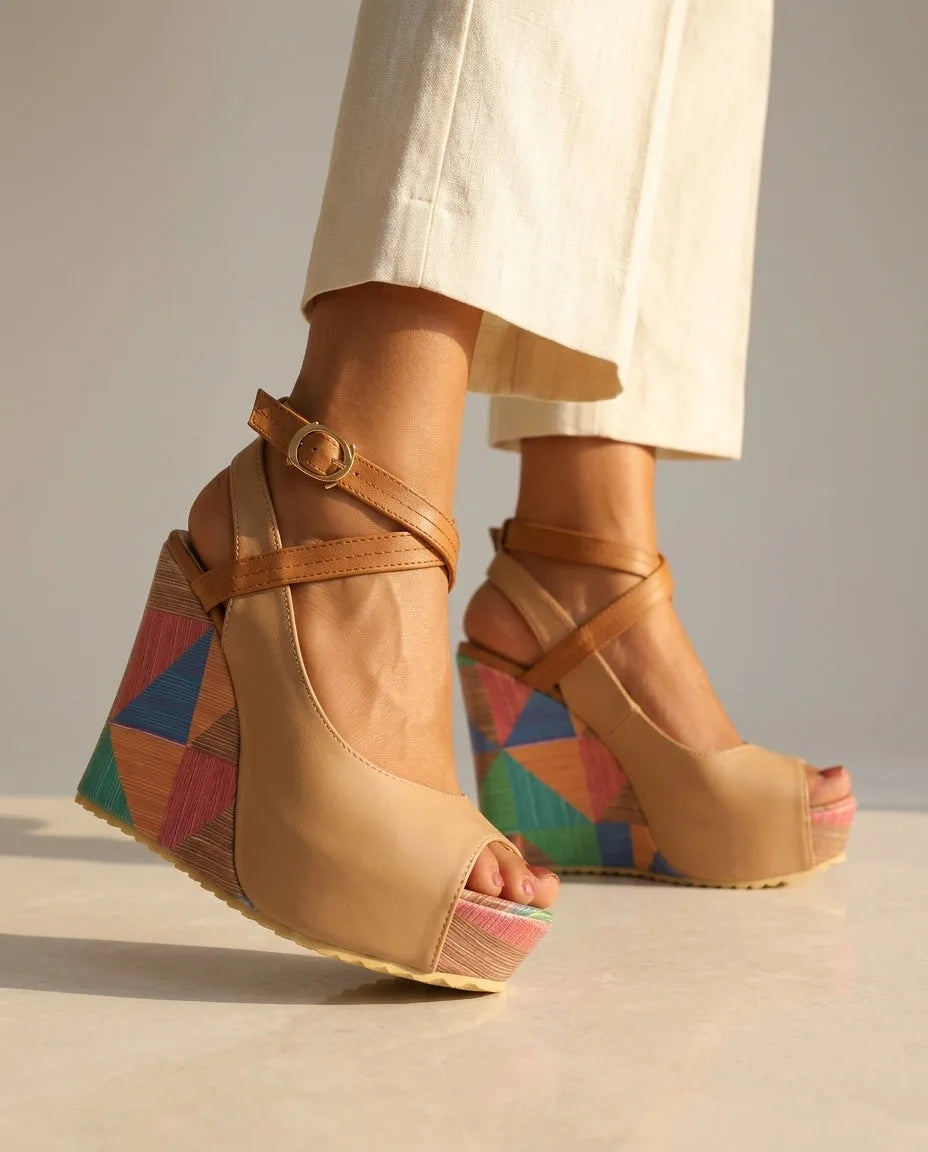 Angled view of tan platform wedge sandal with open toe, crossed ankle straps and multicolour triangle-patterned wedge heel