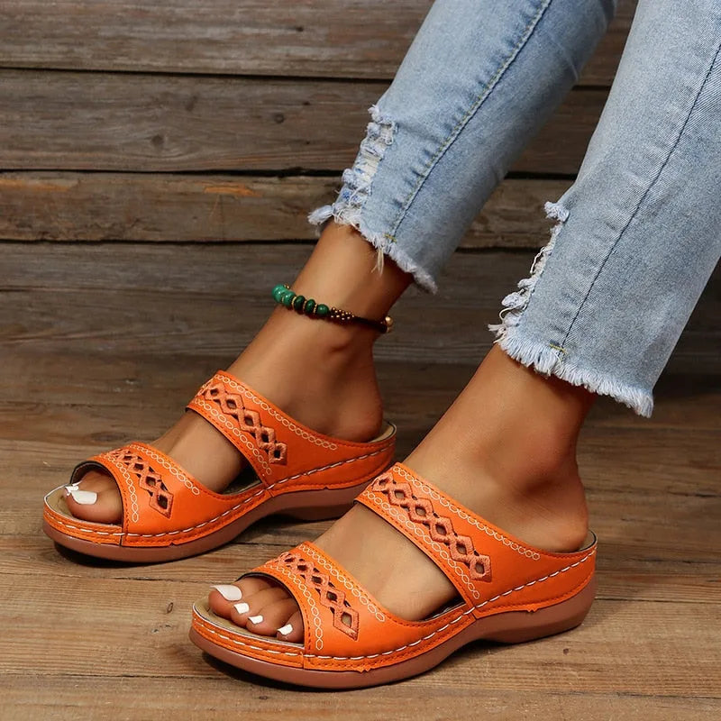 Orange wedge sandals with open-toe strap design and diamond cutout pattern, close-up side view