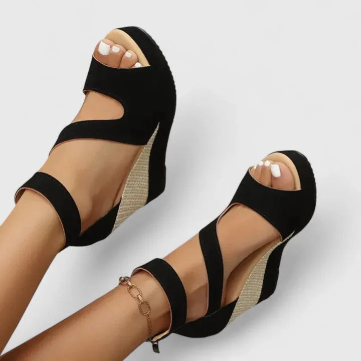 Top-down view of both feet in black open-toe wedge sandals showing woven platform heel