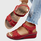 Red wedge sandal with adjustable hook-and-loop straps, shown from above revealing the padded tan footbed and side cutouts