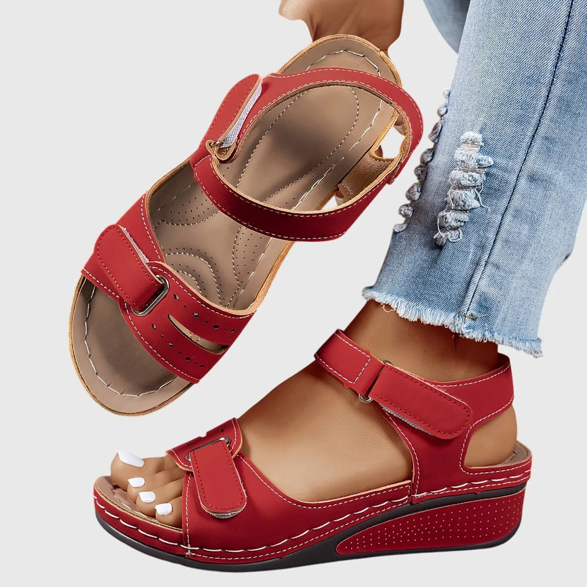 Red wedge sandal with adjustable hook-and-loop straps, shown from above revealing the padded tan footbed and side cutouts