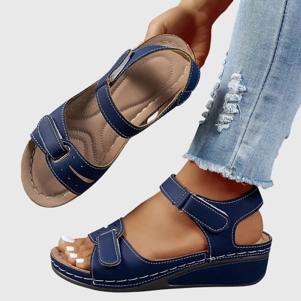 Navy blue wedge sandal shown on foot, highlighting the low block wedge and open heel design