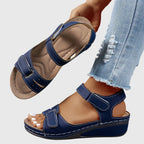Navy blue wedge sandal shown on foot, highlighting the low block wedge and open heel design