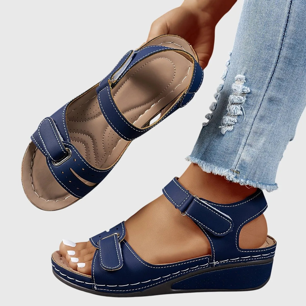 Navy blue wedge sandal shown on foot, highlighting the low block wedge and open heel design