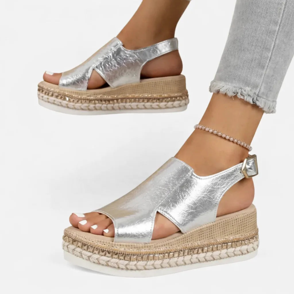 Angled view of silver wedge sandals showing the crossover open-toe strap and woven platform midsole