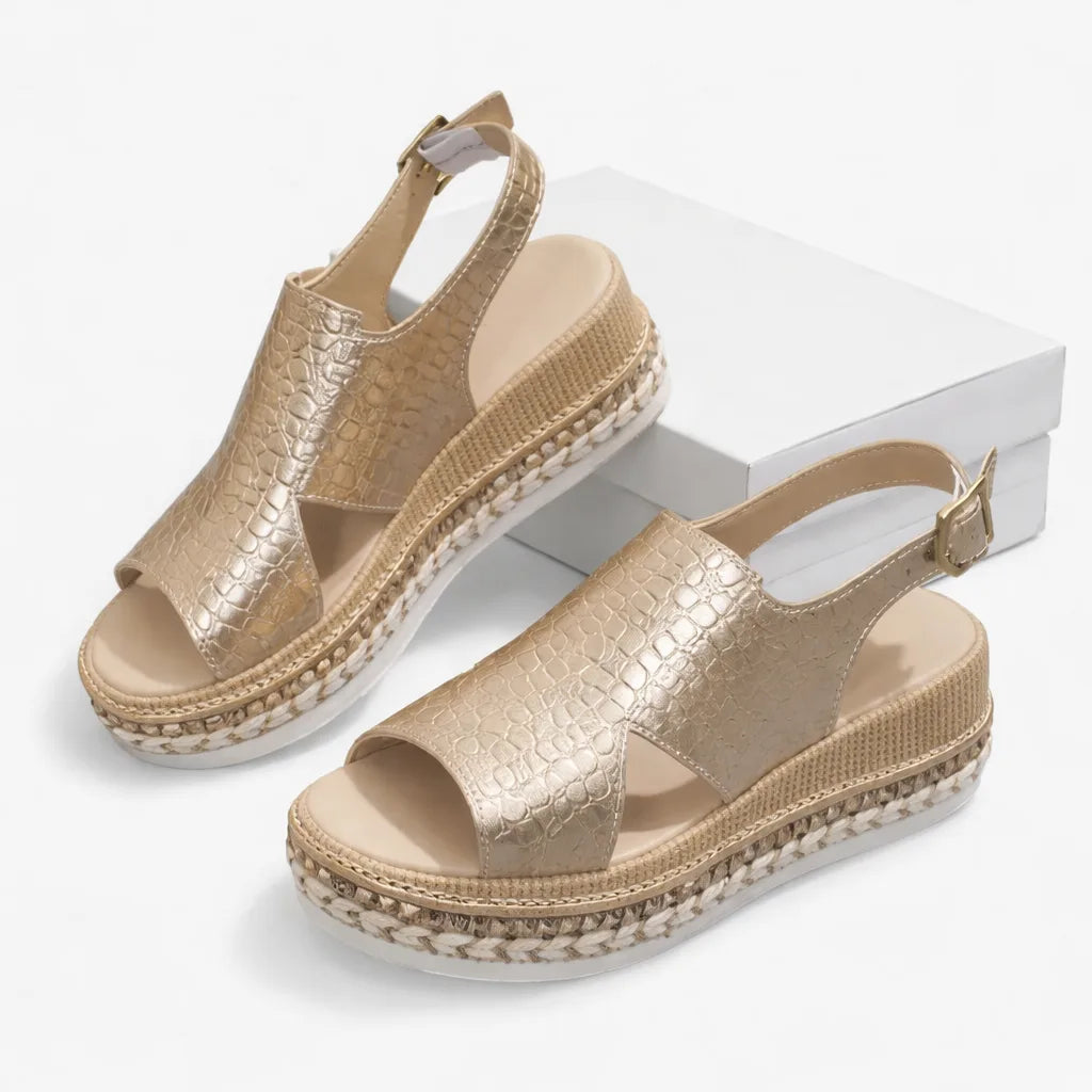 Pair of gold croc-effect wedge sandals displayed beside a white shoebox, showing the full platform sole