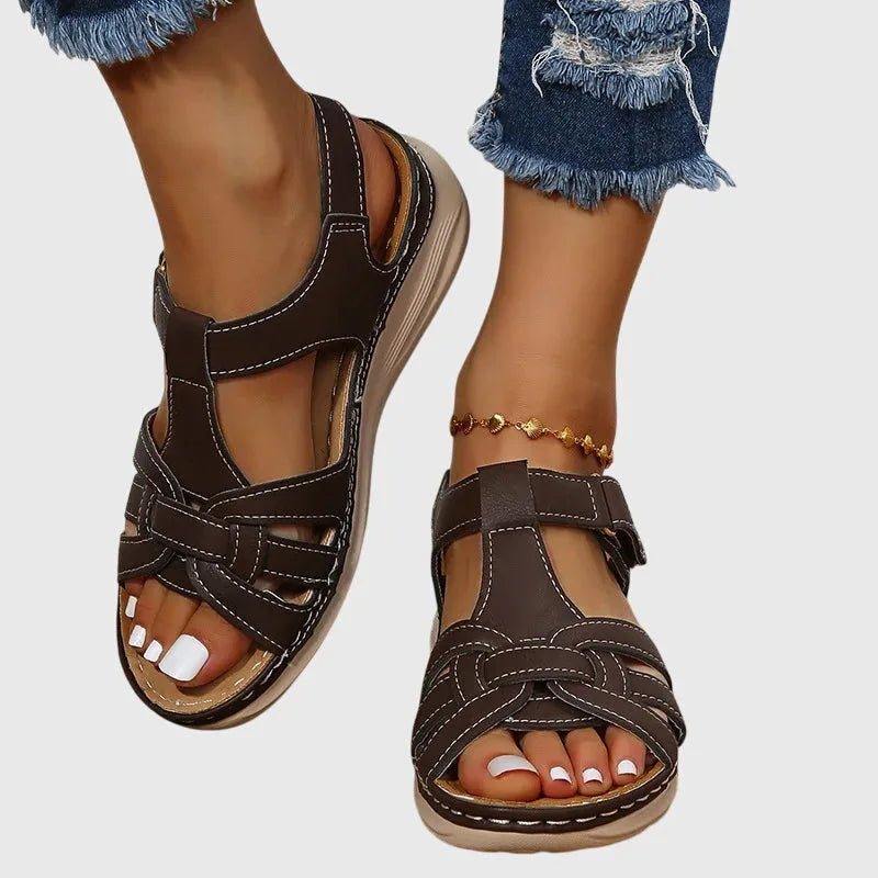 Close-up of dark brown woven leather sandal with stitched wedge sole and adjustable ankle strap